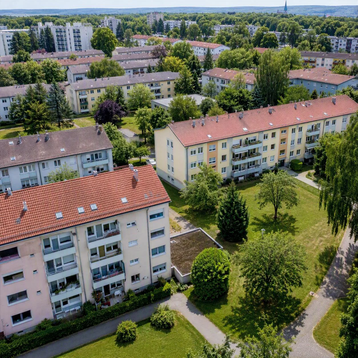 Mehrfamilienhäuser mit roten Dächern im Grünen aus der Luft